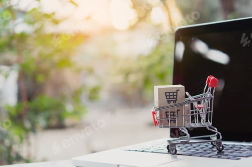 Preview: Shopping online. Cardboard box with a shopping cart logo in a trolley on laptop keyboard.