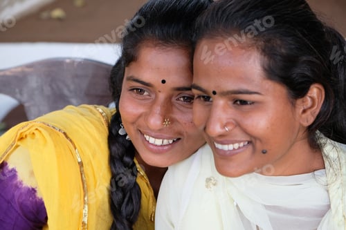 Preview: Two happy smiling Indian female friends enjoying their time in a cafe looking at something