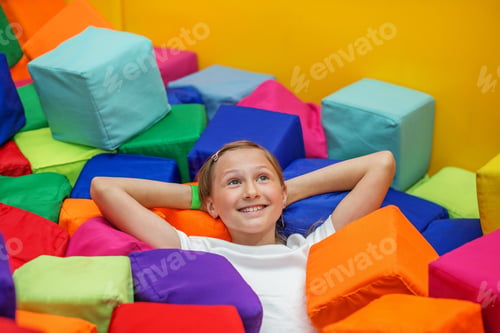Preview: Happy tween girl relaxing in colorful foam pit
