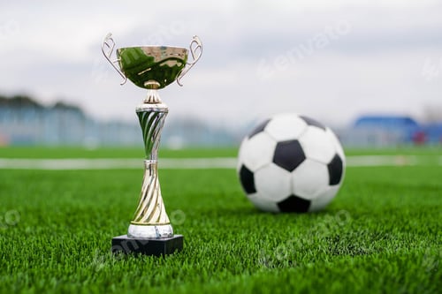 Preview: Golden football cup with soccer ball on field.