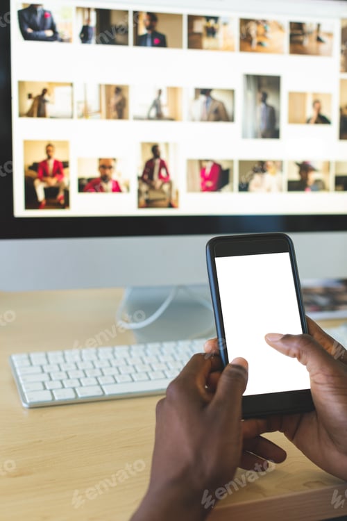 Preview: Close-up of young African-American businessman using mobile phone at desk in office