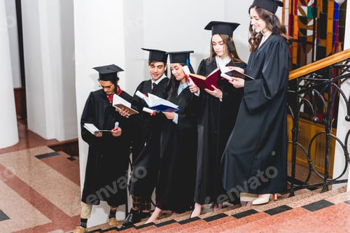 Preview: happy students in graduation caps holding diplomas and reading books