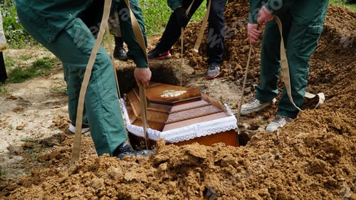 Preview: Burial. Men lower the coffin into the grave.