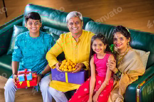 Preview: Indian family siutting with gift box on sofa on diwali festival night