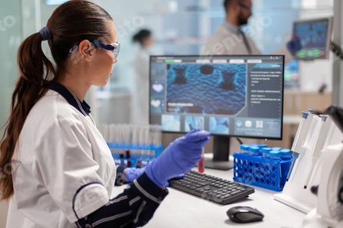 Preview: Chemistry doctor analysing blood sample and typing on computer
