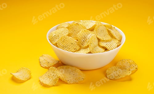 Preview: Ridged potato chips in bowl on yellow background