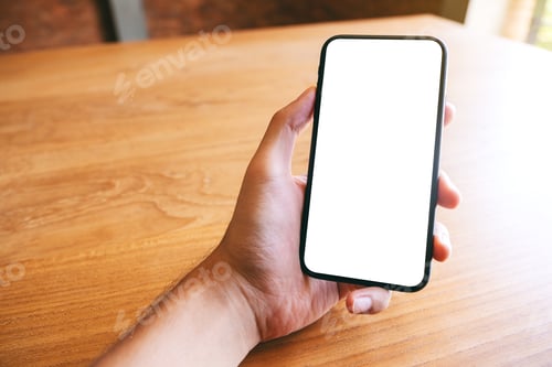 Preview: Mockup image of a hand holding black mobile phone with blank white screen on wooden table