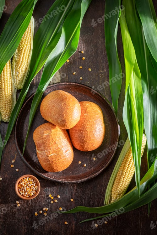 Preview: Fresh and healthy corn buns on dark table and plate.