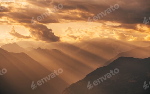 Preview: Amazing dramatic cloudscape in sunset with sun rays over misty mountains landscape
