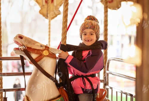 Preview: A little girl rides on a carousel, winter holidays.