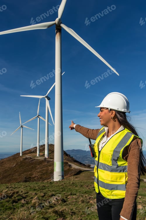 Preview: Female engineer pointing at wind turbines: green energy and sustainability