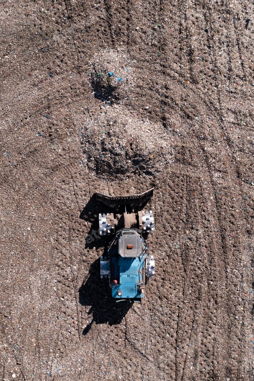 Preview: Aerial view directly above a bulldozer moving waste on a landfill site