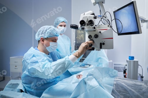 Preview: Male Surgeon Performing Operation Using Surgical Microscope in Operating Room