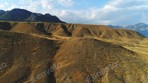 Preview: Close-up view of sand and gravel hills and ravines near the mountains covered with green shrubs and