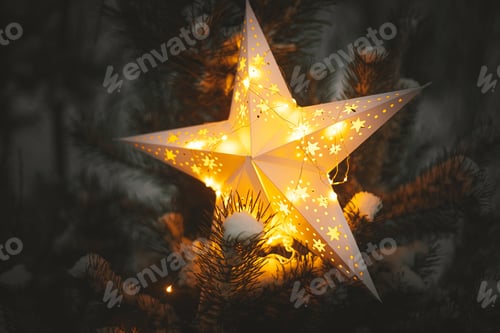 Preview: Merry Christmas! Christmas star glowing on snowy tree in night, close up. Atmospheric magic winter
