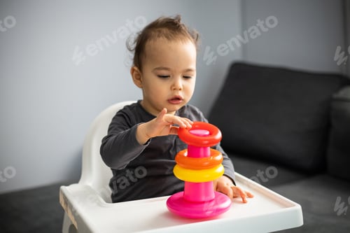 Preview: Cute little baby boy sits in high chair and plays with pyramid. Early development of child.