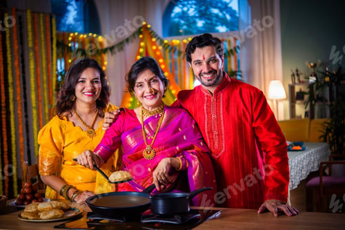 Preview: Indian family in traditional wear cooking food for diwali festival celebration at home - group photo