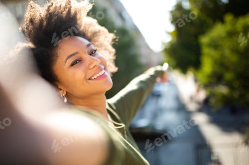 Preview: Smiling young african american woman taking selfie outdoors