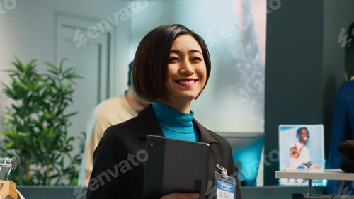 Preview: Asian employee checking clothes inventory on tablet
