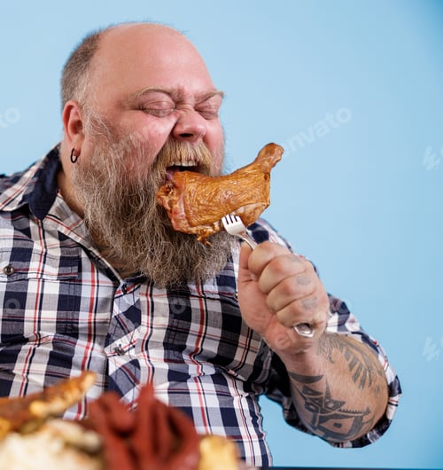 Preview: Bearded man with overweight bites piece of chicken leg on light blue background