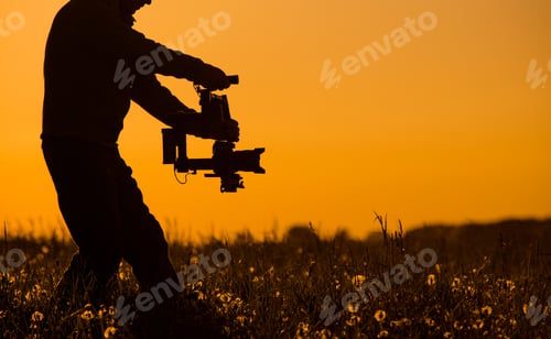 Preview: Camera Operator Works During Sunset Near Flowers