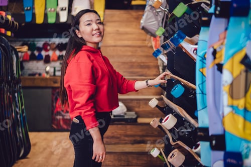 Preview: Young Woman Shopping for Skateboards in Shop