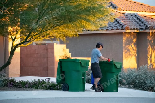 Preview: Man putting out the garbage bins for trash collection.