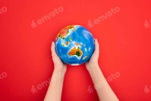 Preview: Cropped view of woman holding globe on red background, global warming concept