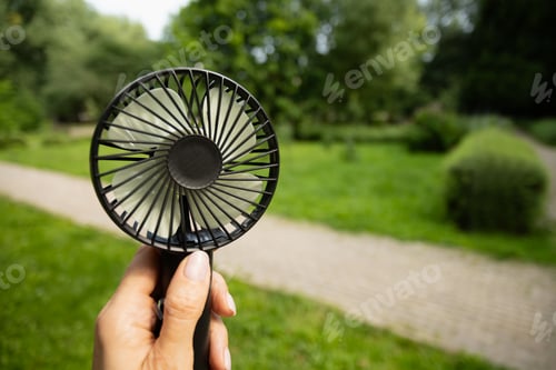 Preview: Hand Holding Portable Fan in Park Setting