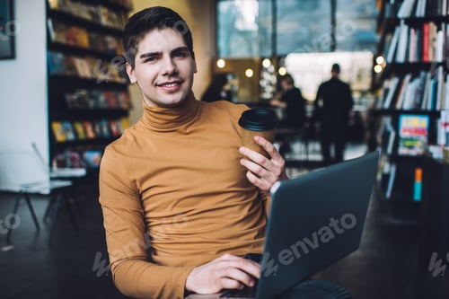 Preview: Cheerful man with cup of coffee browsing laptop