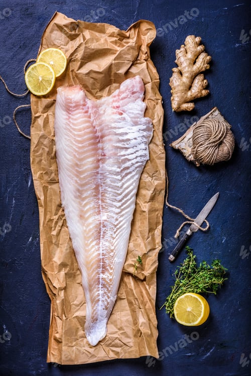 Preview: top view of raw fish fillet with lemon, ginger, rope and knife on blue