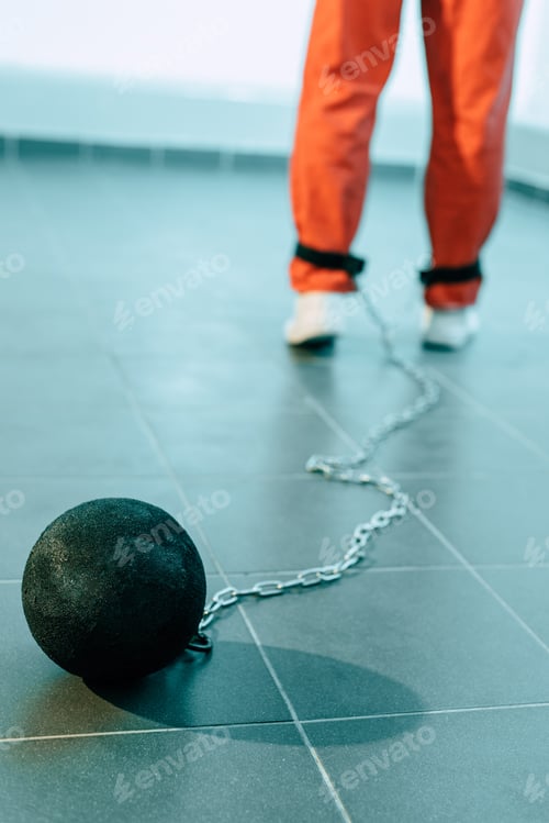 Preview: cropped image of prisoner in orange uniform with weight tethered to leg