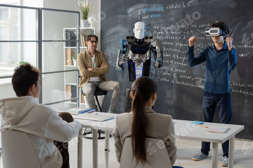 Preview: Teenage student with vr headset demonstrating abilities of robot by blackboard