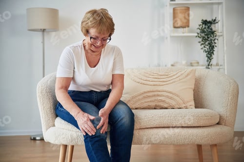 Preview: Pain in the leg. Senior elderly woman is at home in the living room