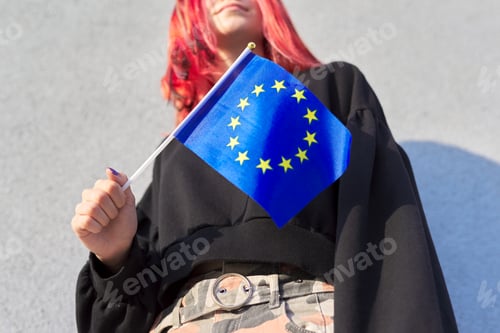 Preview: Female student teenager with EU flag in hand, gray outdoor wall background