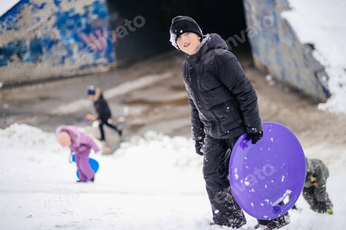 Preview: chick carries an ice sled to slide down a snow-covered slide in winter