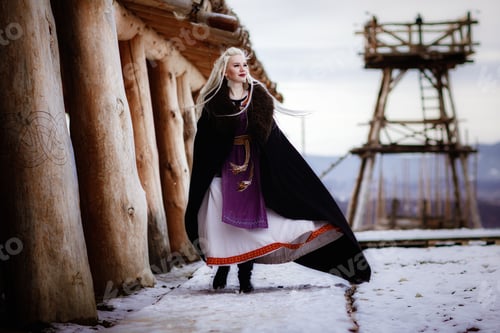 Preview: Beautiful blonde Viking dressed in a black cloak against the backdrop of the castle