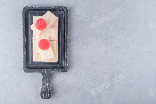 Preview: Stack of wafers topped with marmelades on a black tray on marble background