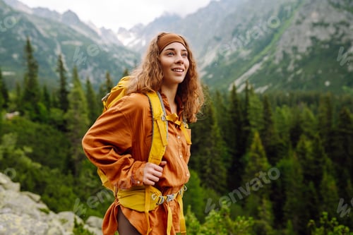 Preview: Young traveler woman with a yellow backpack on a cliff. Sports concept, traveler. Active lifestyle.