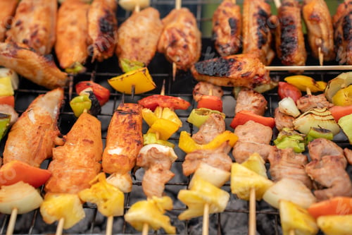 Preview: Assorted delicious grilled meat with vegetables on barbecue grill with smoke and flames.