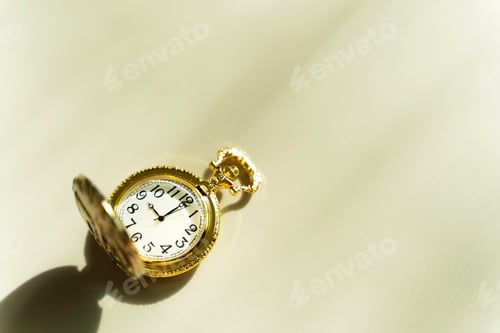 Preview: Time background concept. Golden pocket watch on table with sunlight and free copy space for text.