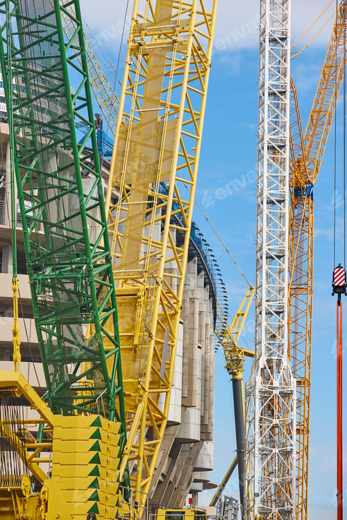 Preview: Telescopic cranes under a blue sky. Construction engineering industry
