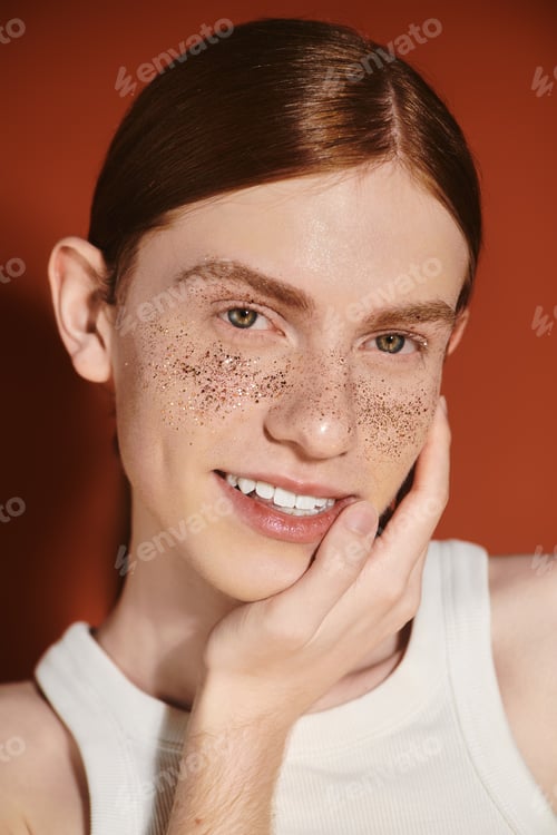 Preview: A confident young queer man with red hair shows off his stylish look while smiling with freckles