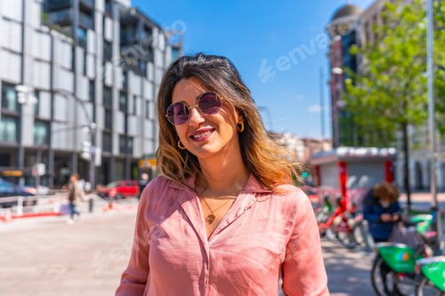 Preview: Smiling woman wearing sunglasses enjoying sunny day in the city
