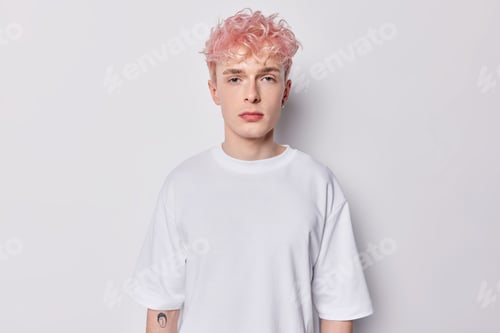 Preview: Portrait of attentive hipster guy with pink hair and tattoo on arm dressed in casual basic t shirt