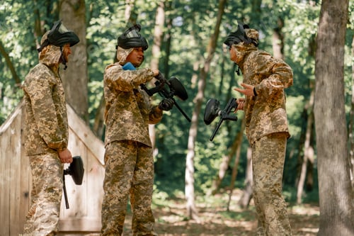 Preview: in the forest in middle of the field pintball players discuss and gesticulate how to play the game