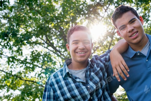 Preview: Two young men outdoors, one with his arm around the shoulders of the other.