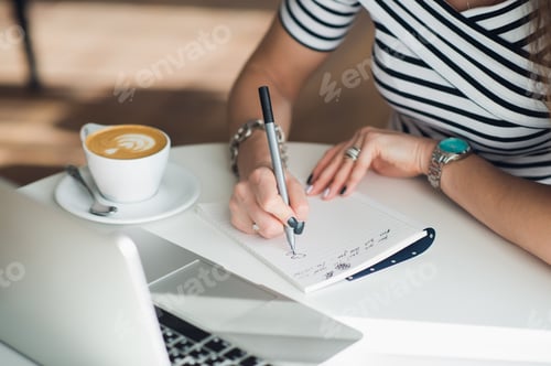 Preview: A white blank notebook with a luxury pen and a cup of Latte coffee with blurred laptop in the