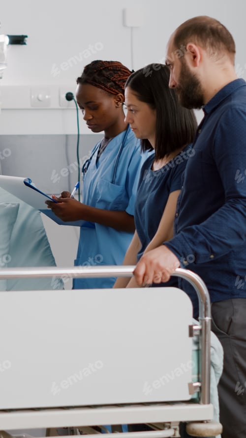 Preview: Physician pediatric doctor monitoring disease symptoms while african american nurse checking IV drip