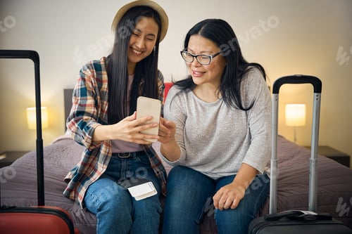 Preview: Two tourists using mobile phone in hotel room on arrival